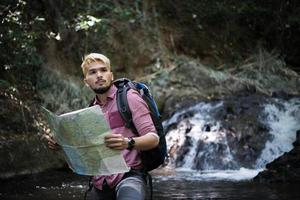 Hombre de aventuras observando el mapa en un camino de montaña foto