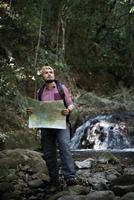 Hombre de aventuras observando el mapa en un camino de montaña foto