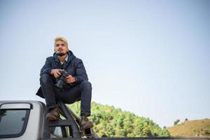 Young photographer sitting on his pickup truck photo