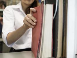 Young students finding books in university library photo