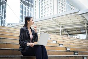 Business woman using laptop sitting on steps photo