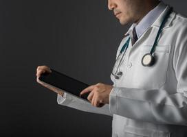 Joven médico sosteniendo un tablet pc aislado sobre fondo gris