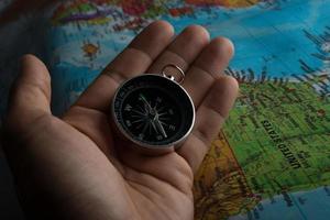 Man holding a compass on top of a map photo