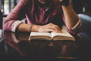 Joven hipster barbudo leyendo un libro en un café foto