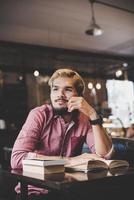 Joven hipster barbudo leyendo un libro en un café foto