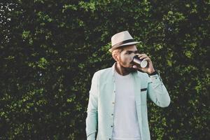 Happy hipster man holding hot coffee photo