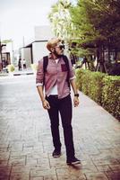 Retrato de un hombre guapo hipster en jeans y gafas de sol caminando foto