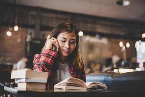 Hipster teenager sitting and enjoying a book at a cafe photo