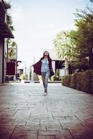 Portrait of young stylish hipster woman walking on urban street, smiling enjoy weekends. Vintage toned. photo