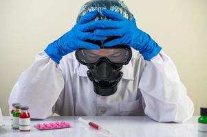 Scientist at the table with vaccines and drugs photo