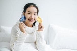 Mujer joven con una tarjeta de crédito sonriendo en la cama foto