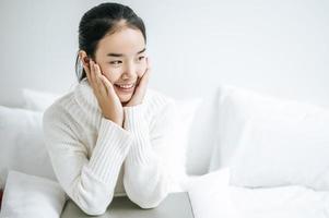 Young woman sitting on her bed with hands touching cheeks photo