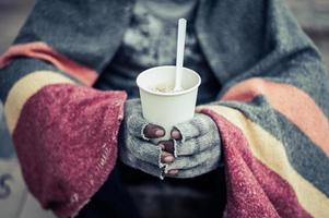 Homeless man wrapped in cloths and eating noodles photo