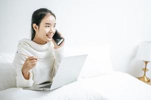 Woman playing on her laptop and talking on the phone photo