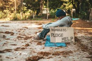 mendigo sentado en la calle con mensajes para personas sin hogar por favor ayuda foto