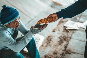 Begging under the bridge with a person who handing them bread photo