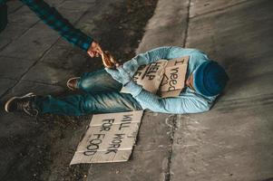 Beggar under the bridge with cardboard help signs photo