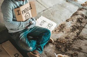 Beggars sitting under the bridge with a sign photo