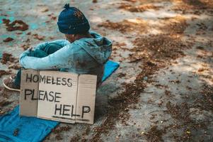 Beggar sleeps on the street with homeless messages please help photo