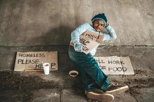 Beggar sitting under the overpass with a please help sign photo