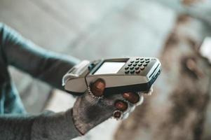 Mendigo sentado debajo de un paso elevado con una máquina de tarjeta de crédito foto