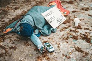 mendigo duerme en la calle con máquina de tarjeta de crédito foto