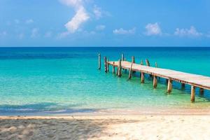 Muelle de madera en la playa con cielo azul nublado foto