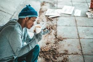 pidiendo limosna bajo el puente con una taza que contiene monedas y fideos instantáneos foto