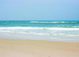 Ocean waves on beach with clear blue sky photo