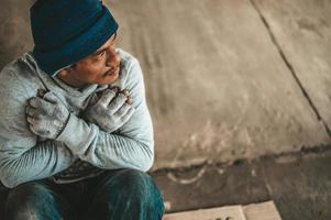 Beggar sitting under the overpass with a please help sign photo