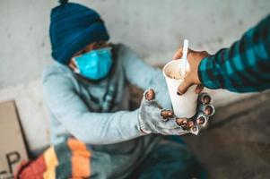 Beggar sitting under the overpass and accepting noodles from someone photo