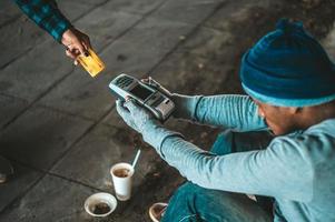 Beggars sitting under the bridge with a credit card swipe machine photo