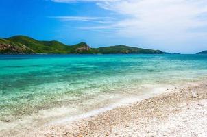 Tropical island rock on the beach with cloudy blue sky photo