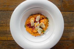 risotto con camarones en plato blanco y mesa de madera foto