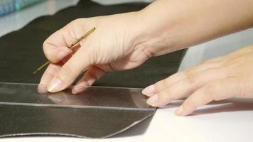 Leather tailor is working with her handmade product with ruler