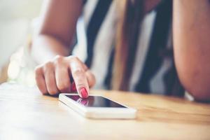 Primer plano de las manos de la mujer tocando el teléfono celular con pantalla de espacio de copia en blanco foto