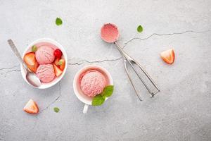 Strawberry ice cream flavour in white bowl setup on concrete background photo