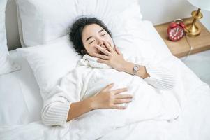 Young woman wearing white shirt just waking up in bed photo