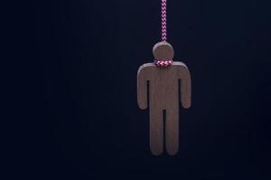 Wood figure hanged with rope on black background photo
