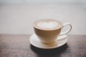 Café latte art vintage con forma de corazón en la mesa de madera foto