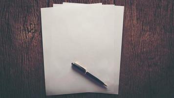 Blank sheet of paper and pen on a wooden table photo