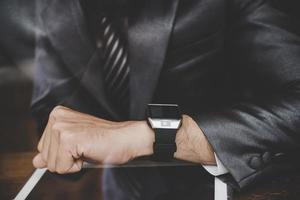 Young businessman sitting at cafe bar, looking at watch photo