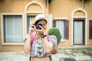 Retrato de mujer bastante joven hipster divirtiéndose en la ciudad con cámara foto