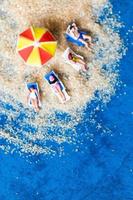 Figurilla en miniatura de personas tomando el sol en la playa foto