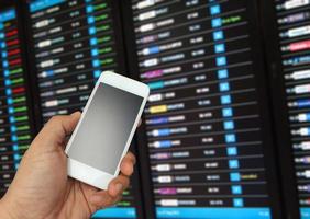 Hand holding phone near flight board photo