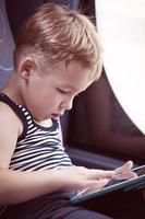 Child using tablet while traveling by bus photo