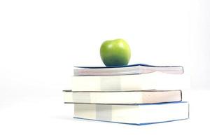 Pile of books with green apple white background photo