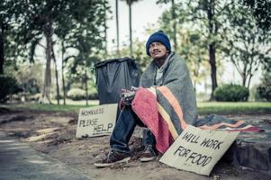 Hombre sin hogar con cartel de cartón foto