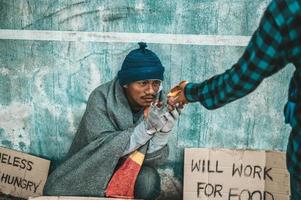 Person gives to a beggar on the side of the road photo