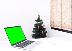 portátil en el escritorio con maqueta de árbol de navidad foto
